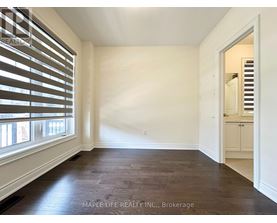 A room with wooden floors and white walls, with a doorway leading to another room.