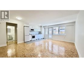 A spacious kitchen with white appliances and a wooden floor.