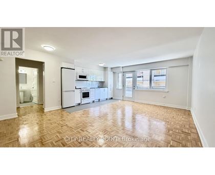 A spacious kitchen with white appliances and a wooden floor.