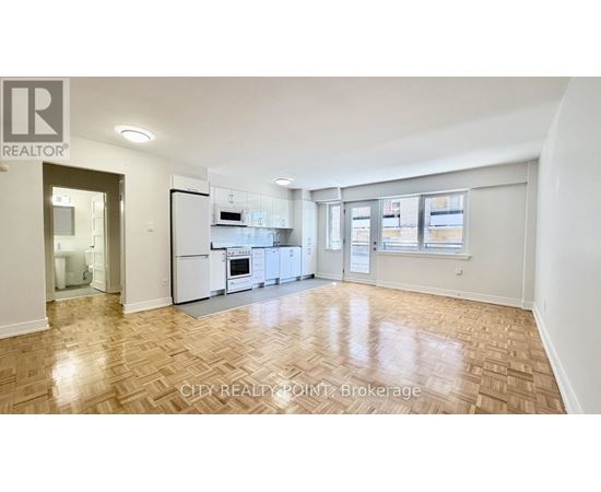 A spacious kitchen with white appliances and a wooden floor.