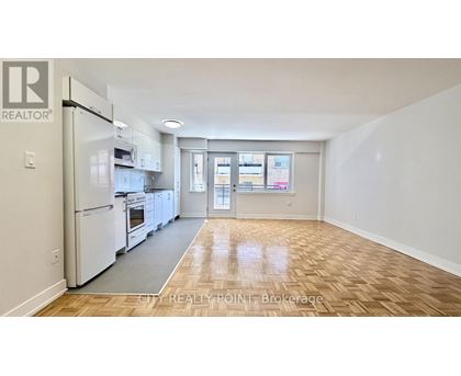 A kitchen with white appliances and wooden floors.