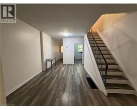 A hallway with a staircase and a door at the end.