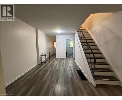 A hallway with a staircase and a door at the end.