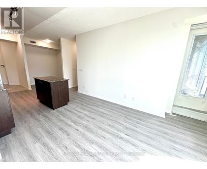 A spacious living room with a grey carpet and a wooden cabinet.