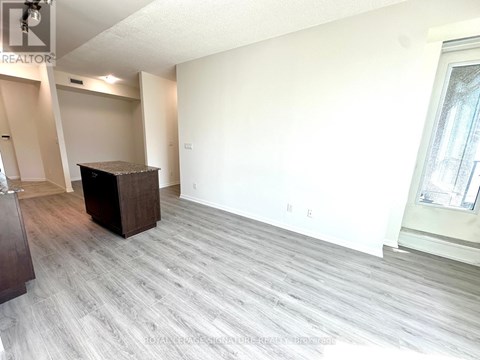 A spacious living room with a grey carpet and a wooden cabinet.
