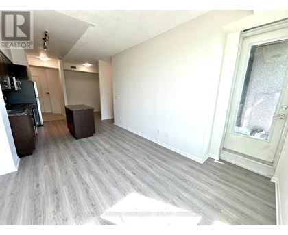 A spacious room with light wood flooring and white walls.
