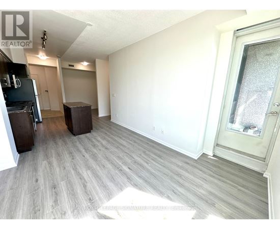 A spacious room with light wood flooring and white walls.