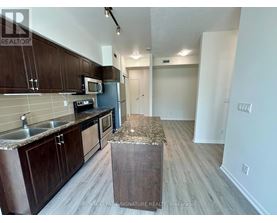 A kitchen with dark wood cabinets and a granite counter top.