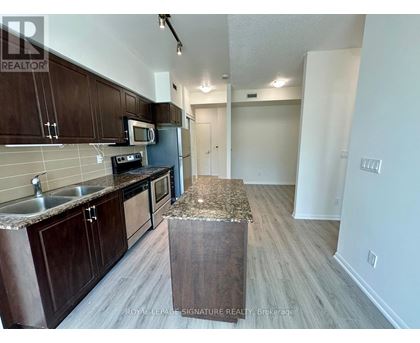 A kitchen with dark wood cabinets and a granite counter top.