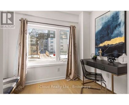 A room with a desk and a window showing an apartment building outside.