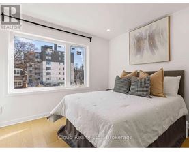 A bedroom with a large bed and a window overlooking a residential area.