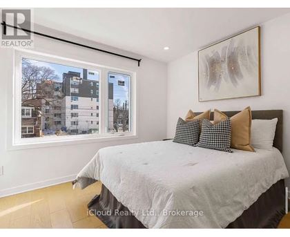 A bedroom with a large bed and a window overlooking a residential area.