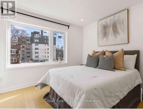 A bedroom with a large bed and a window overlooking a residential area.