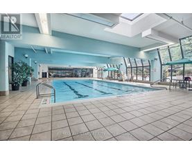 A large indoor swimming pool with a tiled floor and a glass wall.