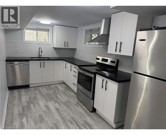 A kitchen with white cabinets and a stainless steel refrigerator.