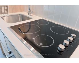 A modern kitchen with a stainless steel stove top and a sink.
