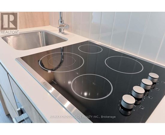 A modern kitchen with a stainless steel stove top and a sink.