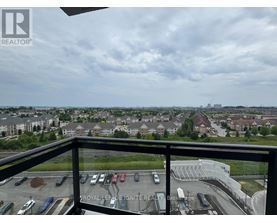 A view from a balcony overlooking a parking lot and buildings.