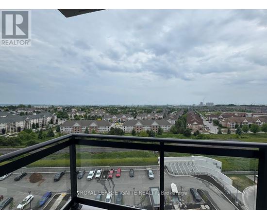 A view from a balcony overlooking a parking lot and buildings.