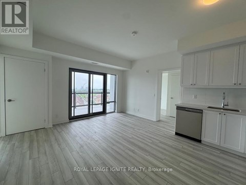 A spacious kitchen with white cabinets and a sink is visible in the image.