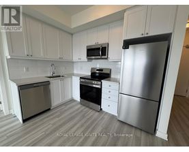A kitchen with white cabinets and a stainless steel refrigerator.