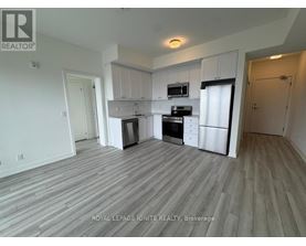 A kitchen with white cabinets and appliances in a room with wooden flooring.