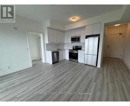 A kitchen with white cabinets and appliances in a room with wooden flooring.