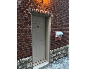 A grey door is on the left side of a brick wall.