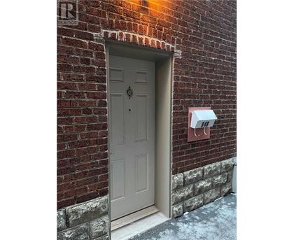 A grey door is on the left side of a brick wall.