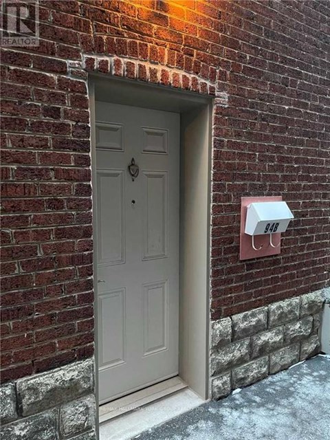 A grey door is on the left side of a brick wall.