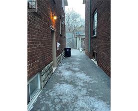 A narrow alley with a brick wall and a metal trash can.