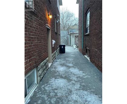 A narrow alley with a brick wall and a metal trash can.