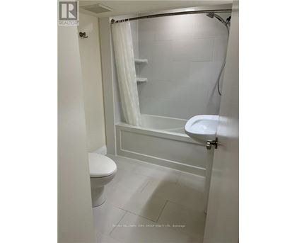 A white bathroom with a toilet, sink, and shower.