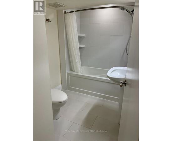 A white bathroom with a toilet, sink, and shower.
