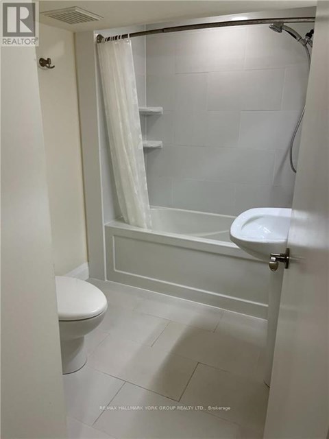 A white bathroom with a toilet, sink, and shower.