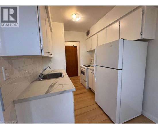 A kitchen with white cabinets and a white fridge.