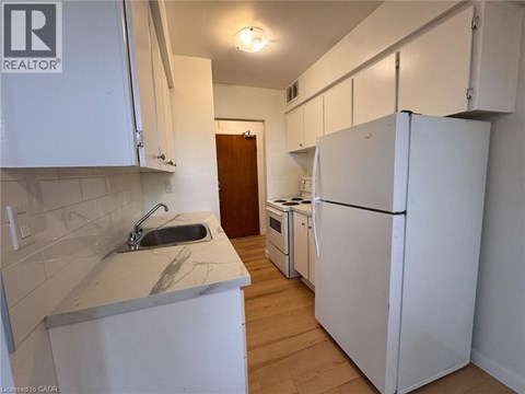 A kitchen with white cabinets and a white fridge.