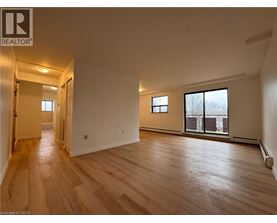 A spacious room with wooden flooring and a large window.