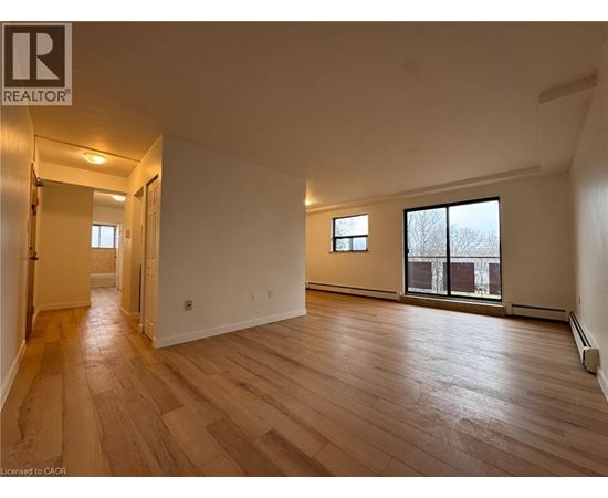 A spacious room with wooden flooring and a large window.