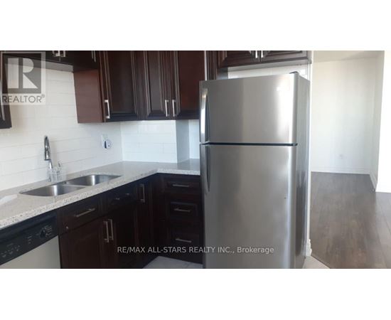 A kitchen with a stainless steel refrigerator and black cabinets.