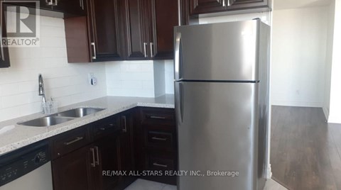 A kitchen with a stainless steel refrigerator and black cabinets.