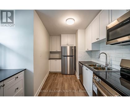 A kitchen with white cabinets and a stainless steel refrigerator.