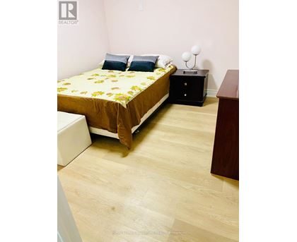 A bedroom with a bed, nightstand, and chair.