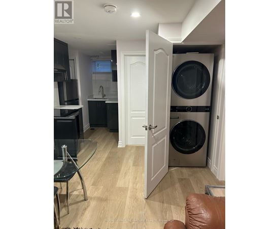 A modern kitchen with a glass table and a washing machine in the laundry room.