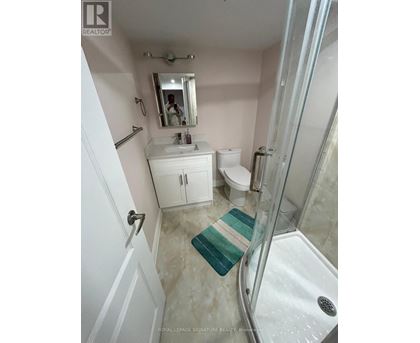 A white bathroom with a glass shower stall and a white toilet.