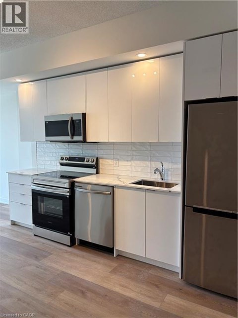 A modern kitchen with white cabinets and stainless steel appliances.