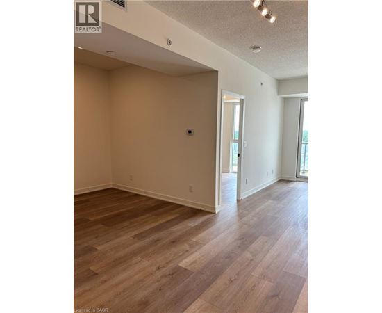 A room with wood flooring and a doorway leading to another room.