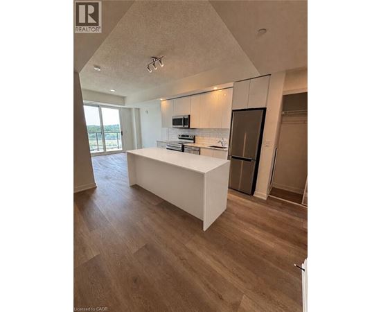 A modern kitchen with a white island and wooden flooring.