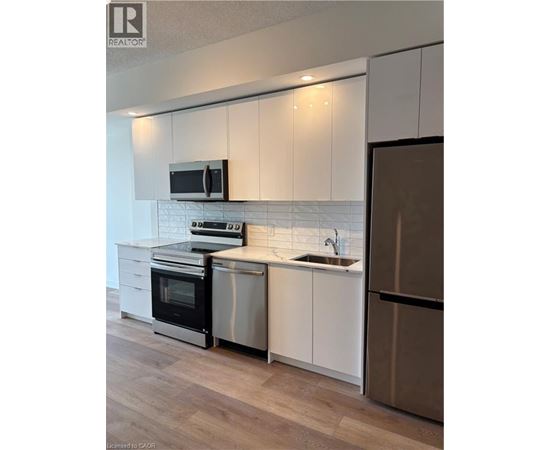A modern kitchen with white cabinets and stainless steel appliances.