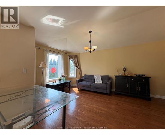 A living room with a glass table and a grey couch.